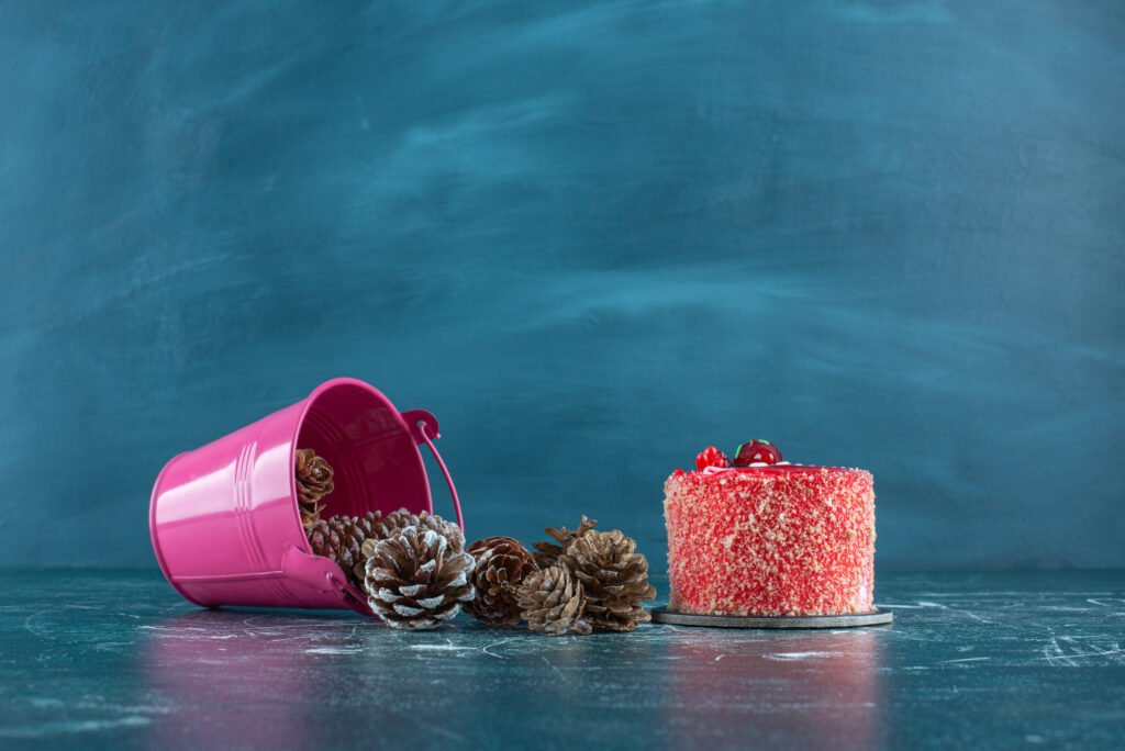 pine cones pouring out of a bucket next to a cake on blue background